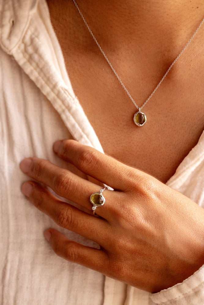 Natural Oval Cabochon light green Peridot and two lab-grown diamonds in an organic style sterling silver ring and a matching pendant.