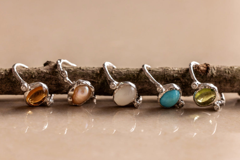 Five rings with colored stones on a wooden branch