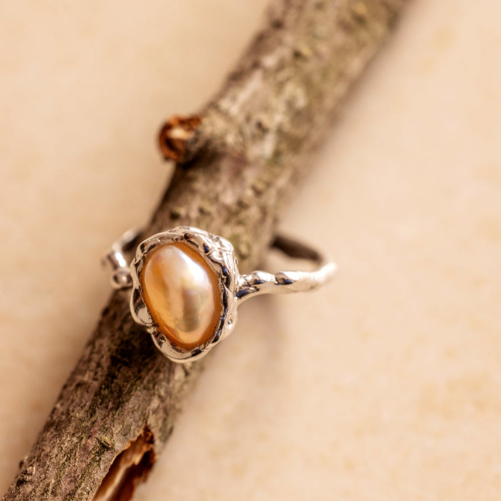 Silver ring with an organic pearl on a wooden branch