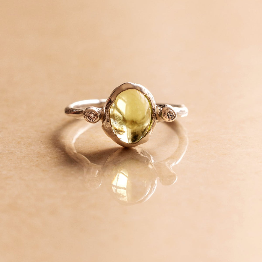Natural Oval Cabochon light green Peridot and two lab-grown diamonds in an organic style sterling silver ring.
