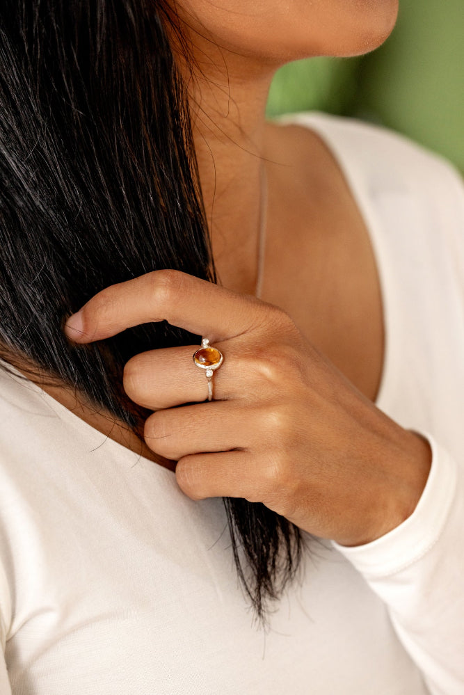 A woman wearing a silver ring and necklace, featuring an organic-style silver ring and a yellow citrine gemstone.