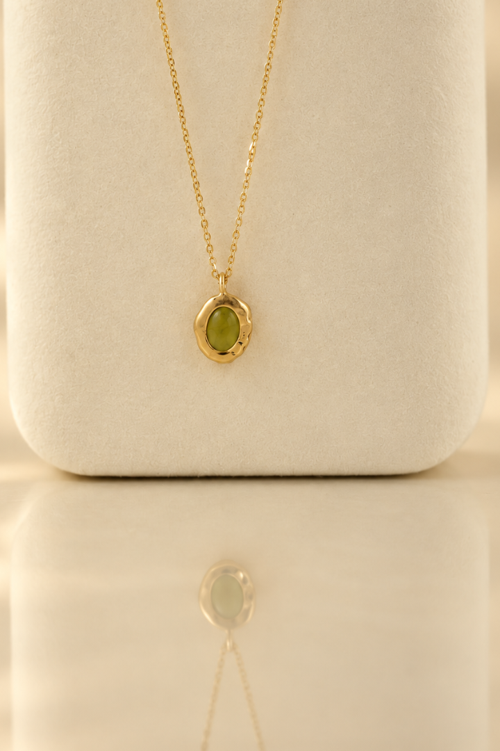 Organic solid 10k gold pendant with a green oval peridot cabochon, handmade by Rooz Jewellery in Toronto