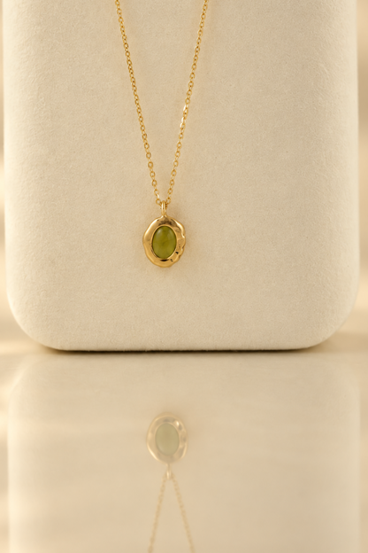 Organic solid 10k gold pendant with a green oval peridot cabochon, handmade by Rooz Jewellery in Toronto