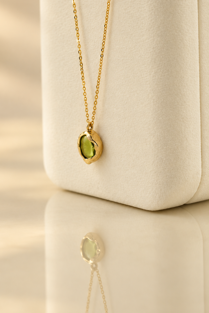 Organic solid 10k gold pendant with a green oval peridot cabochon, handmade by Rooz Jewellery in Toronto