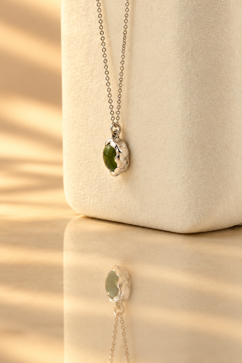 Organic sterling silver pendant with a vivid green oval peridot cabochon, handmade by Rooz Jewellery in Toronto